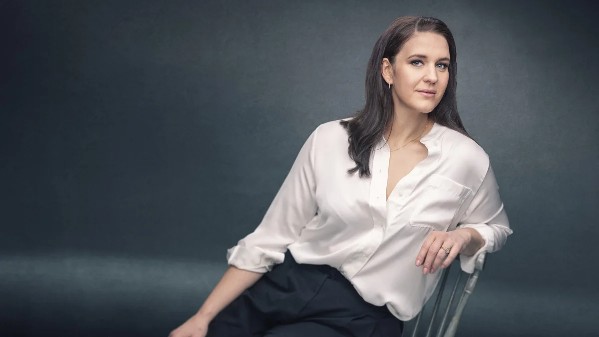 Soprano Lise Davidsen seated in a white shirt against a grey backdrop